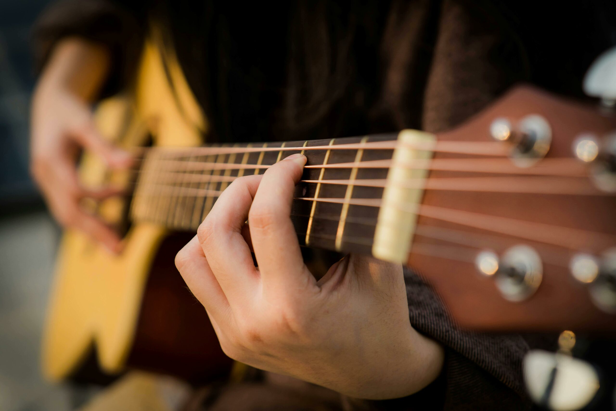 Close view of fingers strumming an acoustic guitar, capturing the essence of music creation.